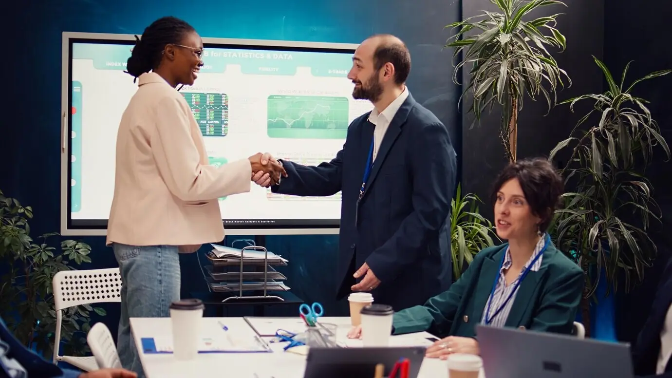 A business manager shakes hands with a new employee during a briefing meeting.
