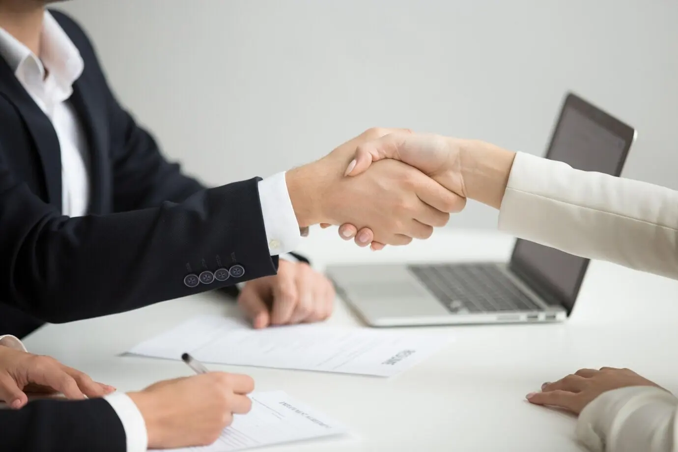 Close-up of HR shaking hands with a successful candidate being hired for a new job.